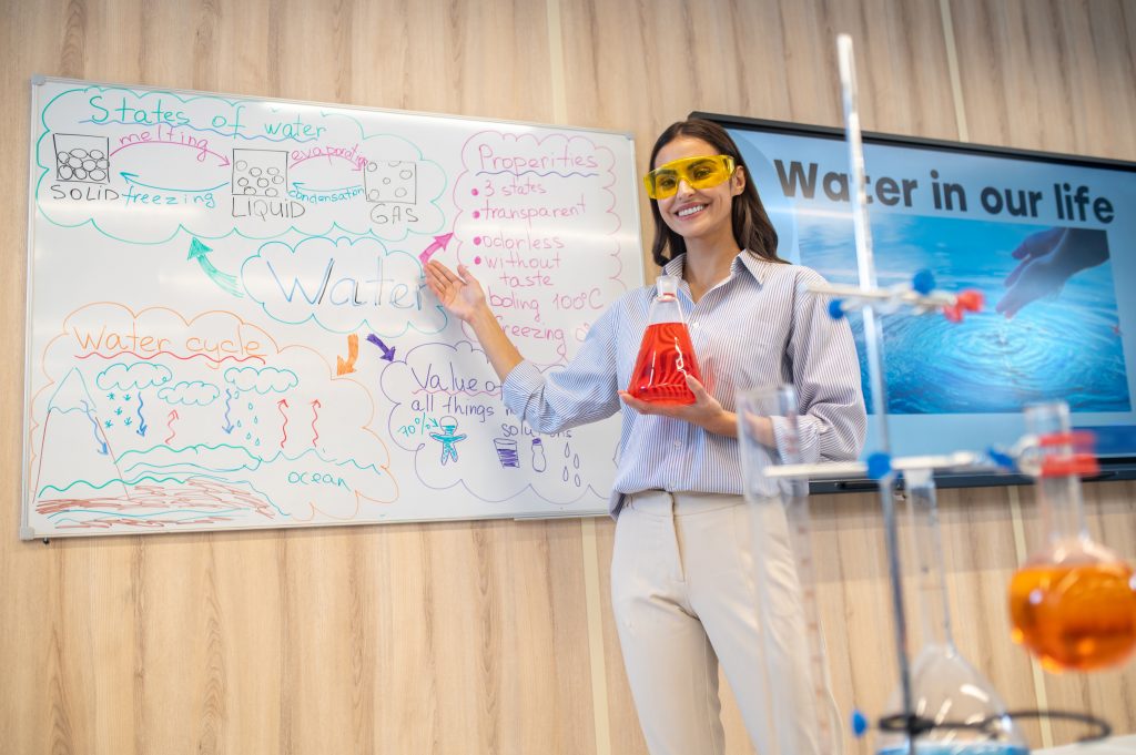 woman with flask near whiteboard looking camera